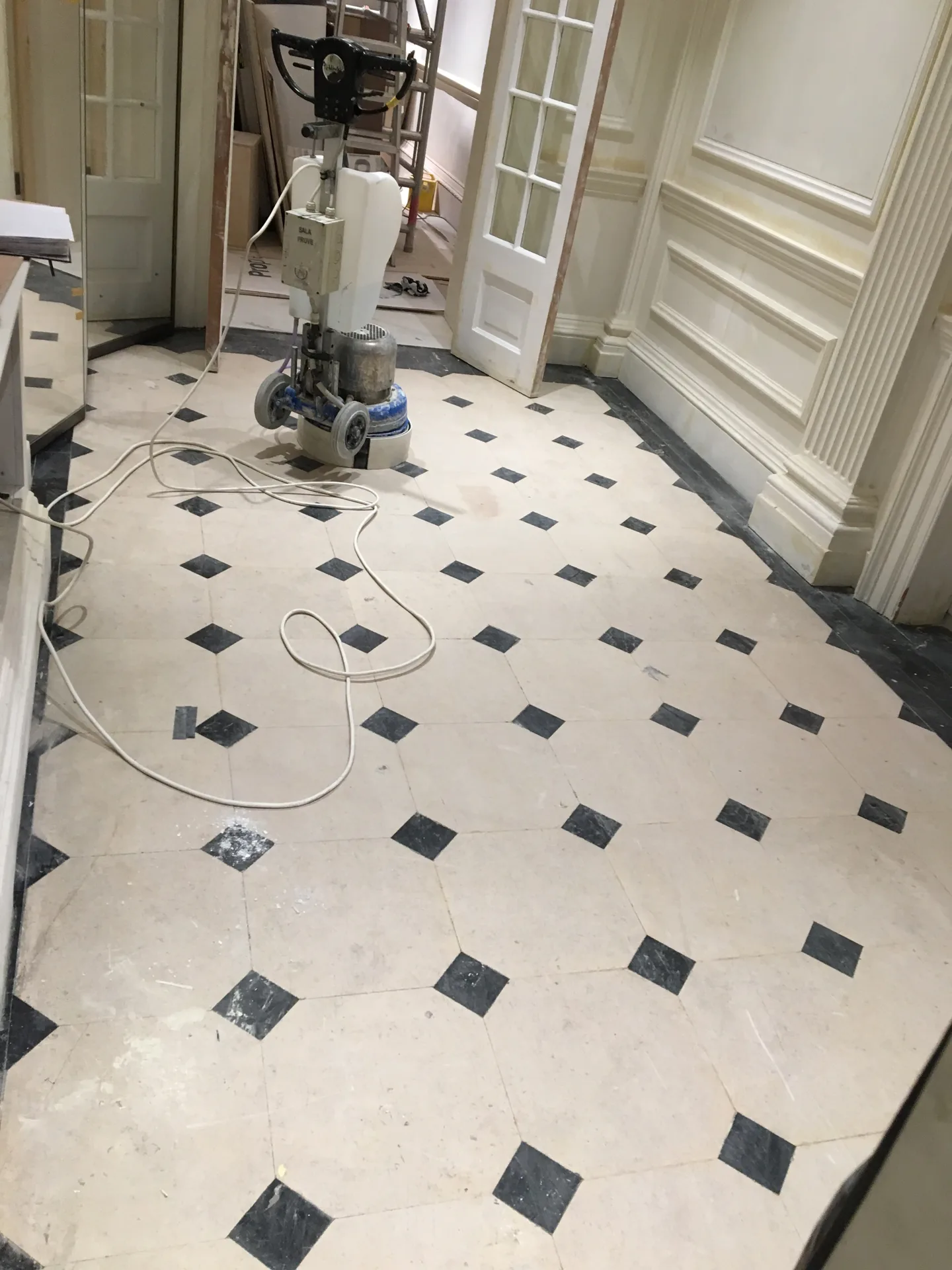 Cream marble hallway floor with black cabochons before full restoration